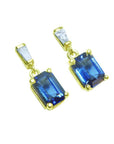 14K yellow gold earrings with emerald cut blue sapphires dangling from baguette diamonds.