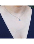 Lady wearing a natural blue sapphire necklace with diamonds 14k white gold dangling pendant