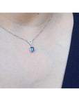 14K white gold necklace with a dangling emerald-cut blue sapphire and pave diamond trillion pendant.