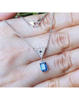 On a hand displaying a natural blue sapphire necklace 14k white gold chain dangling pendant