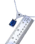 necklace with a blue natural sapphire and white gold chain next to a ruler for scale measure