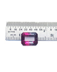 Rectangular pink tourmaline with a ruler for scale on a white background.