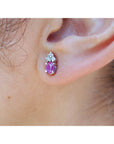 Close-up of an ear wearing a pink cabochon pink sapphire earring in 14k white gold.