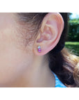 Close-up of a woman wearing a pink sapphire and diamonds stud earring.