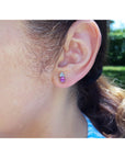 Close-up of a woman wearing a pink sapphire and diamonds stud earring.