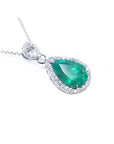 Teardrop-shaped emerald pendant with a halo diamond on a right position and topside view.