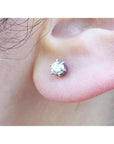 A woman's earlobe wearing a natural diamond stud earring in 14k white gold.