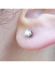 A woman's earlobe wearing a natural diamond stud earring in 14k white gold.