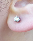 A woman's earlobe wearing a natural diamond stud earring in white gold.