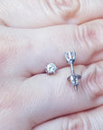 Over a hand displaying a pair of 14k white gold diamond stud earrings screw backs.