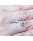 Over a hand displaying a pair of 14k white gold diamond stud earrings screw backs.