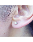 14K white gold natural diamond stud earring with six-prong setting and screw back worn on an ear.