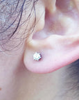 A woman's ear wearing a 14k white gold diamond stud earring crew backs.