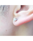 An earlobe wearing a natural diamond stud earring in 14k white gold.
