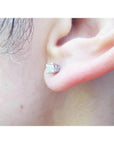An earlobe wearing a natural diamond stud earring in 14k white gold.