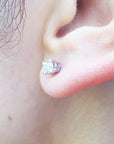 An earlobe wearing a natural diamond stud earring in white gold.