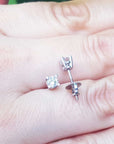 On a hand displaying a screw backs natural diamond stud earrings white gold.