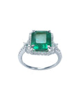 Emerald-cut natural Colombian emerald ring with diamond halo in 14k white gold.