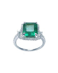 Emerald-cut natural Colombian emerald ring with diamond halo in 14k white gold.