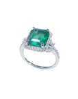 Emerald-cut natural Colombian emerald ring with diamond halo and band in 14k white gold.