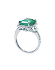 Emerald-cut natural emerald engagement ring in 14k white gold with diamond halo.