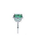 Emerald-cut natural emerald ring with diamond halo and diamond-set 14k white gold band.