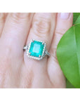 A natural colombian emerald ring for ladies with a halo diamond around the emerald is made of 14k white gold.