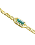 Gold bracelet with a rectangular colombian emerald and accent diamonds on a white background