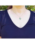 18K yellow gold cross pendant with four round natural Colombian emeralds, worn on a woman's neck.