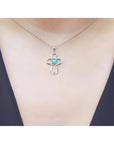 14K white gold cross pendant with a round Colombian emerald and diamond accents on a delicate chain.
