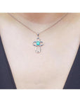 14K white gold cross pendant with a round Colombian emerald and diamond accents on a delicate chain.
