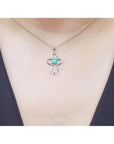 14K white gold cross pendant with a round Colombian emerald and diamond accents on a delicate chain.