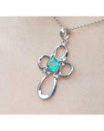 A 14k white gold emerald cross pendant on a chain, worn on a person's neck.
