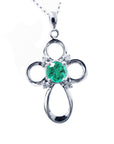 A 14k white gold emerald cross pendant necklace, displaying the topside view.