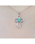 14K white gold cross pendant with a round Colombian emerald and diamond accents on a chain.