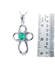14K white gold cross pendant with a round green Colombian emerald and diamond accents, next to a ruler.