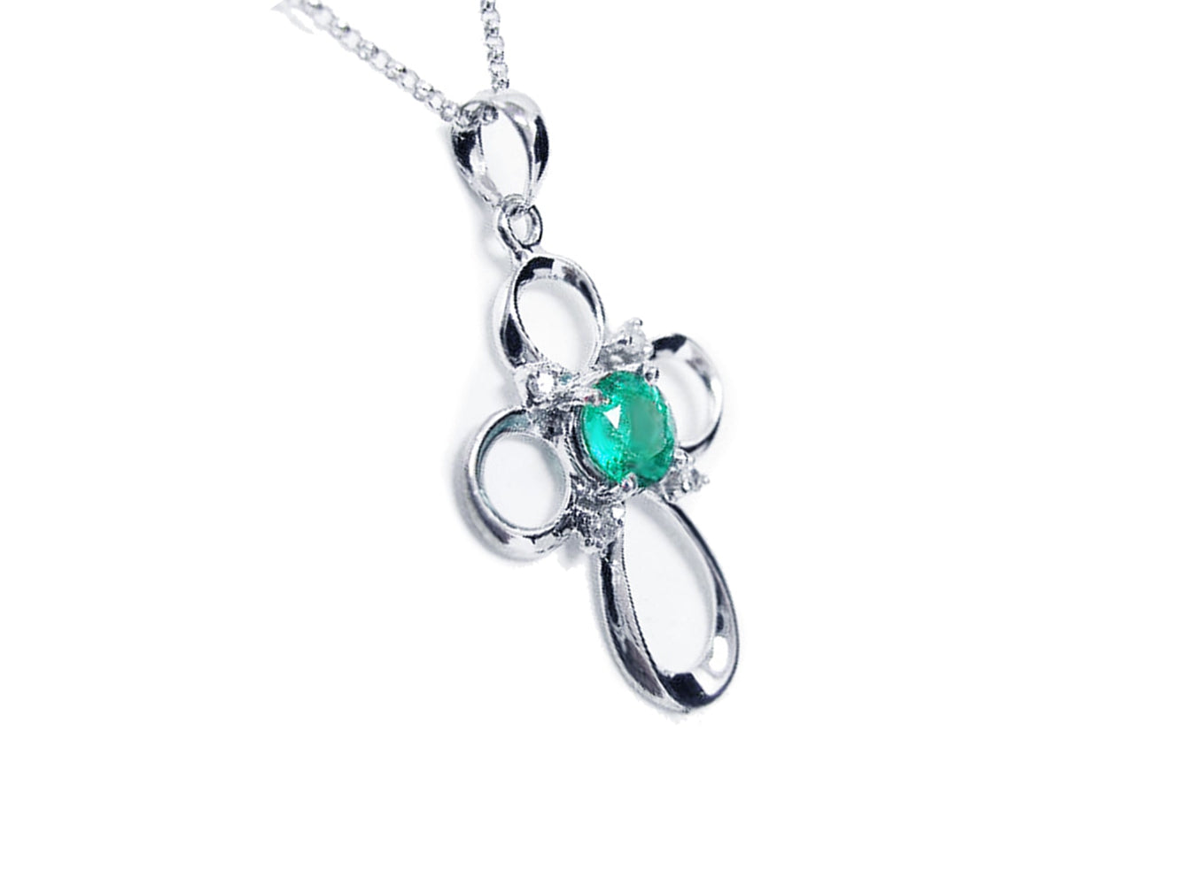 The left-side profile of a white gold emerald cross pendant necklace.