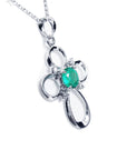 The left-side profile of a white gold emerald cross pendant necklace.