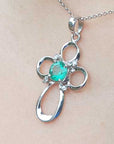 A white gold emerald pendant on a chain, worn on a person's neck.