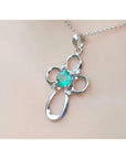 A white gold emerald pendant on a chain, worn on a person's neck.