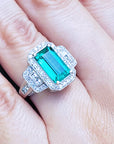 An emerald engagement ring white gold on a hand.