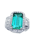Top side view with shoulder profile of a natural Colombian emerald ring on a white background.