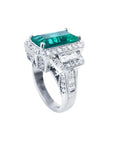18K white gold ring with a vibrant emerald-cut Colombian emerald, haloed by diamonds and baguette side stones.