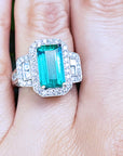A natural Colombian emerald ring, rectangular emerald-cut on a finger.