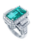 Emerald ring with diamond accents on a white background.