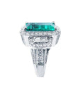 18K white gold ring with a vibrant emerald-cut Colombian emerald, haloed by diamonds and baguette side stones.