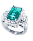 A rectangular emerald with a halo diamond in white gold ring, top side view.