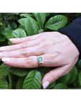 Men's 14K yellow gold ring with a bezel-set natural emerald and diamond accents on a hand.