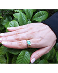 Men's 14K yellow gold ring with a bezel-set natural emerald and diamond accents on a hand.