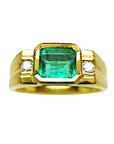 Gold ring for men with a natural emerald and two side diamonds on a topside view position/
